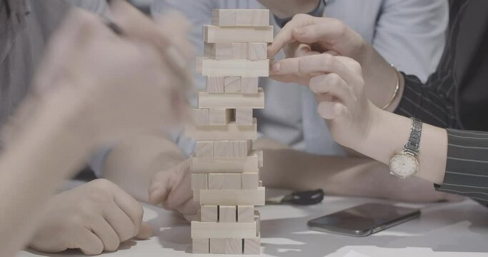Group of unrecognizable millennial Caucasian friends playing Jenga. Young confident men and women enjoying leisure game indoors. Relaxation and friendship. Cinema 4k ProRes HQ.