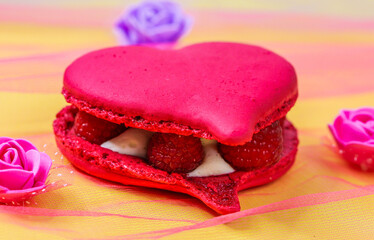 
Macaroon with raspberries and cream.
Heart shaped pink macaroons with raspberries and cream on a yellow background, close-up side view.