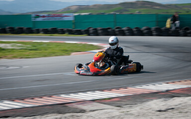 Unrecognised man driving Go-kart with speed in the on a karting track - obrazy, fototapety, plakaty