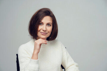 Obraz premium portrait of a young woman brunette 20-30 years of Caucasian appearance, looking at the camera smiling. White warm stylish jacket