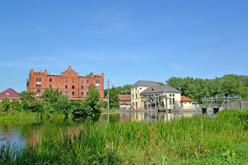Fototapeta na wymiar Cityscape with an old water mill and Ozerskaya hydroelectric station on the Angrap River. Ozersk, Kaliningrad region