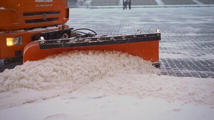 A bucket close-up cleans the sidewalk from snow. The tractor cleans the pavement in winter. Tractor...