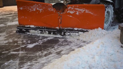 A bucket close-up cleans the sidewalk from snow. The tractor cleans the pavement in winter. Tractor...