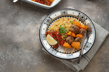 Kebab on skewers with pumpkin and couscous on a plate, copy space