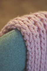 A macro close up of a pink knitted scarf on a grey chair
