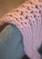 A macro close up of a pink knitted scarf on a grey chair