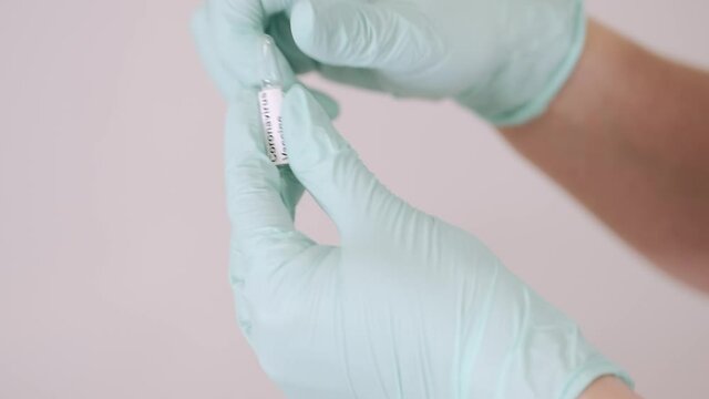 Vaccination concept. Doctor is going to do covid-19 vaccination to a patient. She is opening the ampula.