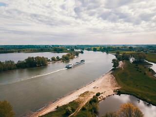 Aerial drone shot of the boat cruising the big river in the Netherlands