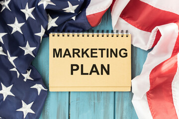 Fototapeta na wymiar Notebook with text marketing plan on table with American flag