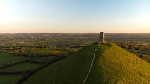 Aerial view of the early morning sunrise over Glastonbury Tor with Somerset fields below.