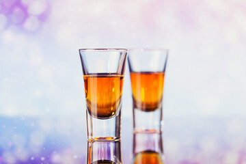 Two glasses of whiskey or bourbon with Christmas decoration on a light bokeh background. New Year, Christmas and winter holidays whiskey mood concept