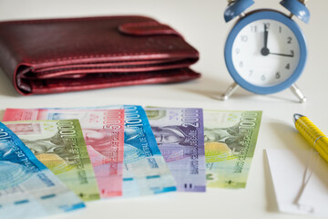 Chile currency, pesos, next to the wallet and the clock showing five to twelve