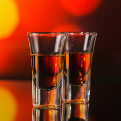 Two glasses of whiskey or bourbon on a red bokeh background. Whiskey mood concept