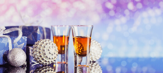 Two glasses of whiskey or bourbon with Christmas decoration on a light bokeh background. New Year, Christmas and winter holidays whiskey mood concept