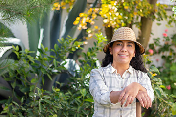 portrait of a young woman in a garden, smiling at camera, wearing a hat