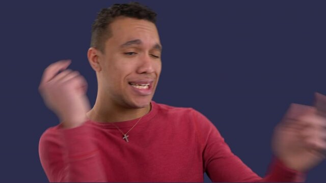 Attractive multiracial man dances happily after getting some good news