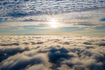 Aerial view from above of white puffy clouds in bright sunny day.