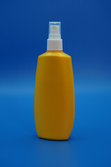 Yellow plastic bottle with sunscreen, close-up on a blue background.