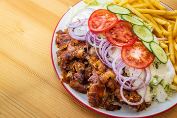 Doner kebab or gyros on a plate with french fries