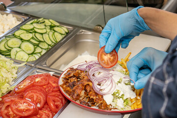 Doner kebab or gyros on a plate with french fries is prepared in the restaurant