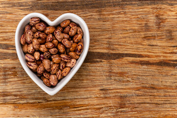 White Cargamanto beans, also known as Cranberry, Borlotti, or Romano beans in a heart-shaped bowl.  Top view.