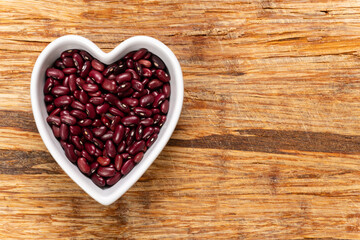 A grain of red bean seeds in a heart-shaped bowl background and texture. Top view.