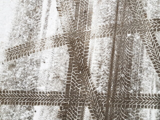 Different cars tire prints on road surface covered with thin layer of snow. Abstract asphalt background.