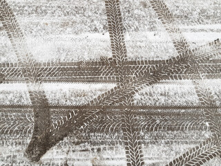 Different tires prints of the cars wheels on road surface covered with thin layer of snow. Abstract asphalt horizontal background.