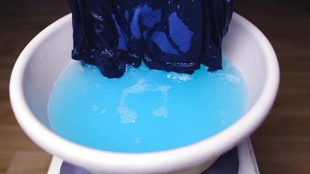 woman washes with her hands blue men's panties in a basin, knitted underwear, clean clothes concept, scandal in the Russian Federal Security Service