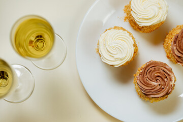 2 glasses with champagne and a plate with sweet pastries.