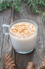 glass cup of salep milky traditional hot drink of Turkey with cinnamon powder and sticks on rustic vintage wooden table. Sahlep background