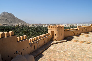 Beautiful view of Nakhal Fort's walls and mountains and a huge orchard of date palms outside it. Nakhal, Oman.