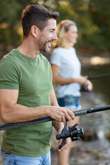beautiful couple fishing in the pond using a fishing rod