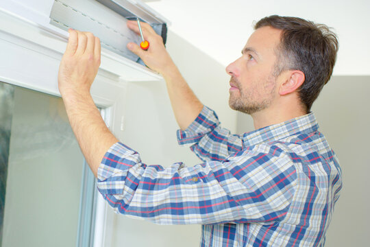 Builder Working On Roller Shutter Door