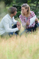 couple in field of long grass looking at paper