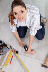 happy young woman measuring and marking laminate floor tile