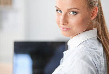 Portrait of smiling receptionist using laptop computer and headset at office desk