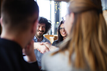 Young successful business people having a meeting at a cafe. Smiling and shaking hands.
