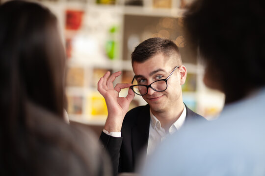Young carefree feminized businessman posing with glasses, looking at camera