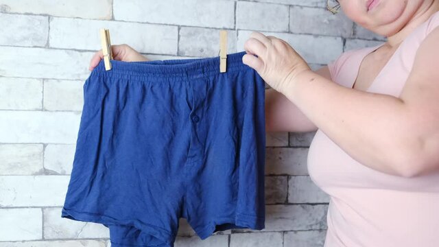 woman holding blue men's underpants in her hands, knitted underwear, concept of comfortable clothes, female intimate problems, scandal in the Russian Federal Security Service