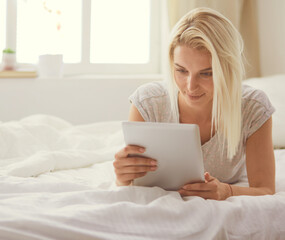 Fototapeta na wymiar Girl holding digital tablet with blank screen and smiling at camera in bedroom