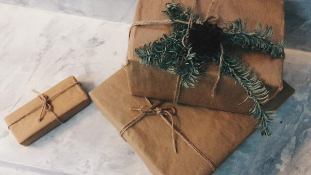 Holiday delivery boxes, parcels wrapped in brown paper, decorated and tied with rough twine, stone background. High quality 4k footage