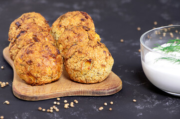 Falafel balls with coriander and parsley on a black background. Fresh vegetarian food. Vegetarian baked falafel with sauce.Healthy food.