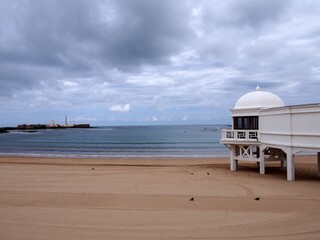 Fototapeta premium Playa of La Caleta, Cadiz, Spa of La Palma in the foreground. In the background, San Sebastian Castle and its lighthouse