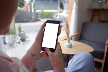 Mockup picture of business woman's hands holding smart phone with white blank screen in modern place.