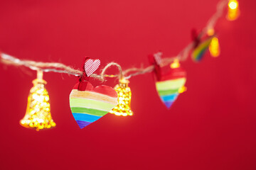 Lgbt valentine's day concept, rainbow heart on garland on red background, copy space
