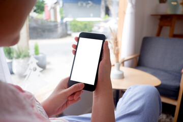 Mockup picture of business woman's hands holding smart phone with white blank screen in modern place.