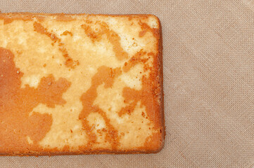 Homemade Sponge Cake, in Portuguese Pão de Ló. Bottom part of the baked cake dough. Isolated on jute background. Top view. Copy space