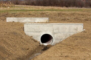 Narrow concrete bridge construction site built over large diameter plastic pipe and storm drain...