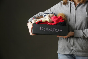 Volunteer women holding donation box with warm woolen wintery clothes, hats, socks, gloves...